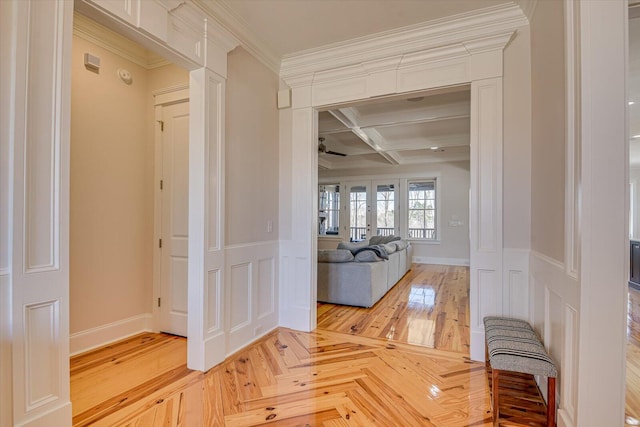 corridor with french doors, a decorative wall, coffered ceiling, and crown molding