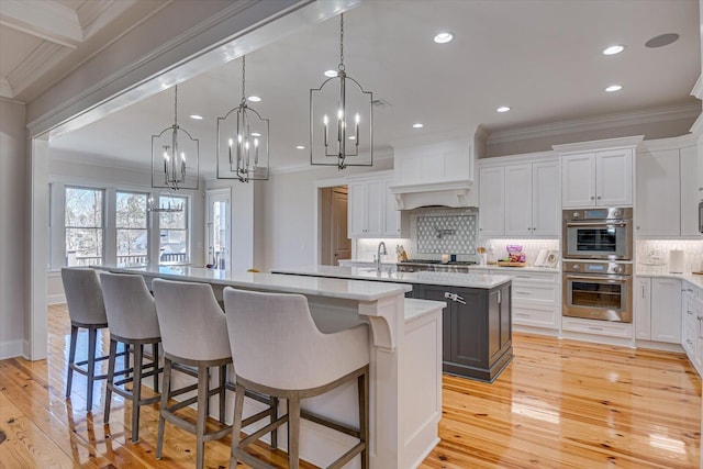 kitchen with stainless steel appliances, a large island, light wood-type flooring, tasteful backsplash, and crown molding