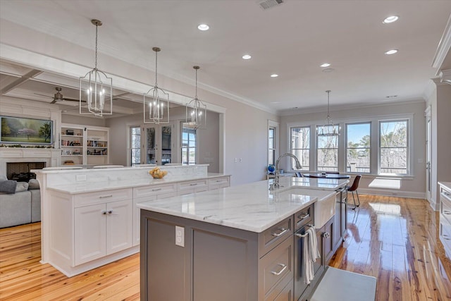 kitchen with open floor plan, a fireplace, a large island with sink, and an inviting chandelier