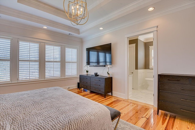 bedroom featuring light wood-type flooring, a tray ceiling, a chandelier, and ornamental molding