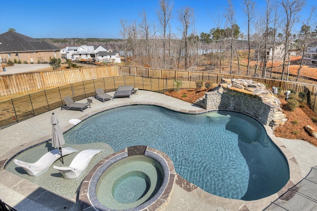 view of swimming pool featuring a fenced backyard, a pool with connected hot tub, and a patio