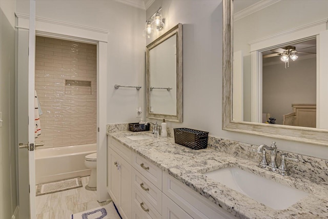 full bath with double vanity, a sink, toilet, and crown molding