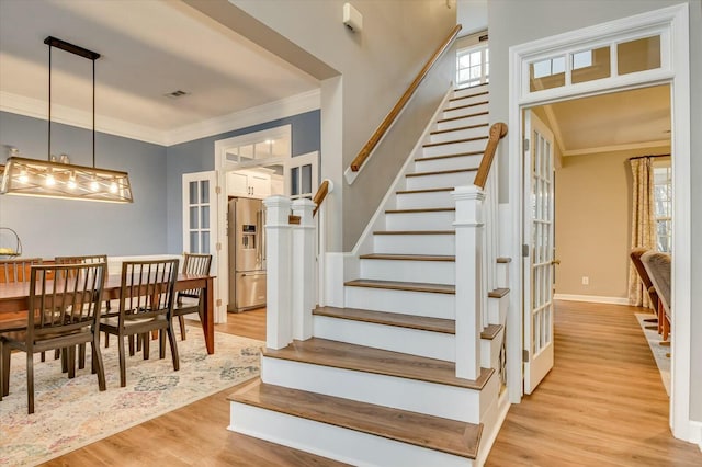 staircase with ornamental molding and wood-type flooring