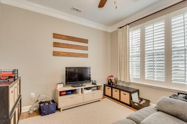 living room with crown molding, ceiling fan, plenty of natural light, and light hardwood / wood-style flooring