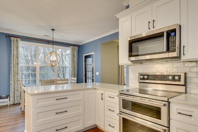 kitchen featuring white cabinetry, crown molding, appliances with stainless steel finishes, kitchen peninsula, and backsplash