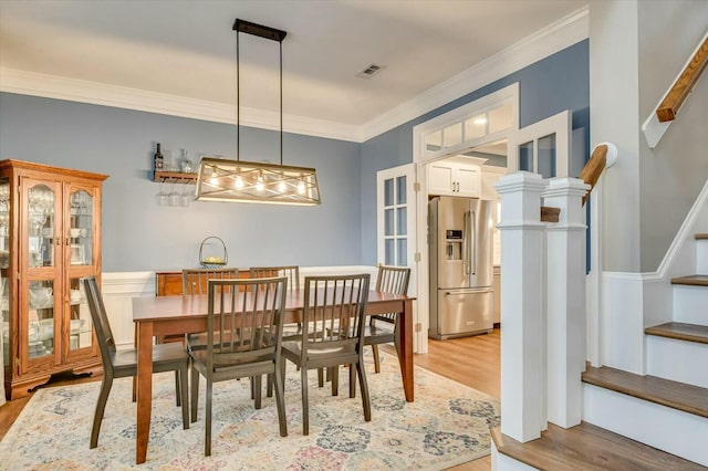 dining space with ornamental molding and light hardwood / wood-style flooring