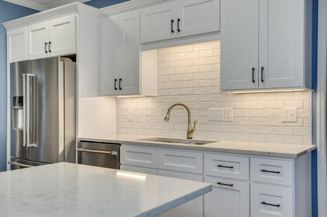 kitchen with stainless steel appliances, white cabinetry, sink, and light stone counters