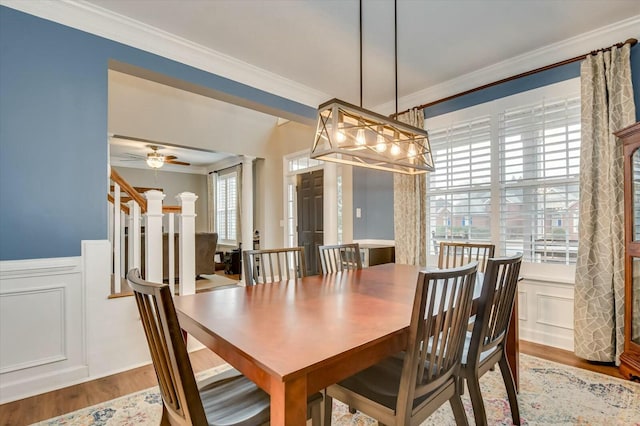 dining area with crown molding, decorative columns, ceiling fan, and light wood-type flooring