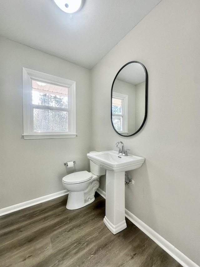 half bathroom with toilet, baseboards, and wood finished floors