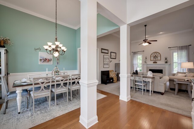 dining area with hardwood / wood-style floors, ceiling fan with notable chandelier, crown molding, and decorative columns