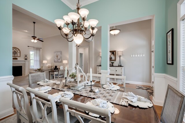 dining space with hardwood / wood-style floors, ceiling fan with notable chandelier, and ornamental molding