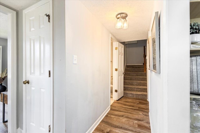 2920 Arrowhead Dr, Augusta, GA 30909 - hallway featuring wood finished floors, a textured ceiling, baseboards, and stairs