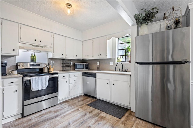 2920 Arrowhead Dr, Augusta, GA 30909 - kitchen featuring appliances with stainless steel finishes, under cabinet range hood, a textured ceiling, light countertops, and light wood-type flooring