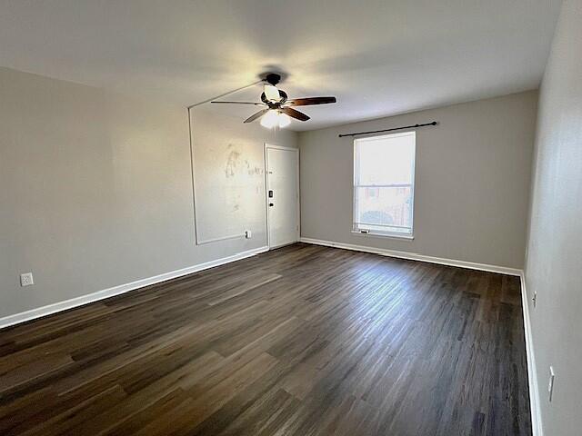 empty room featuring ceiling fan and dark wood-type flooring