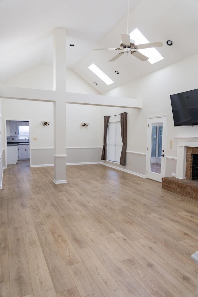 337 Patton Ct, Martinez, GA 30813 - unfurnished living room featuring a skylight, high vaulted ceiling, a fireplace, light wood-style floors, and a ceiling fan