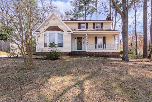 view of front of house with covered porch, a chimney, and fence