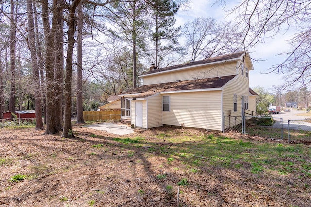 rear view of property with a gate, a chimney, and fence