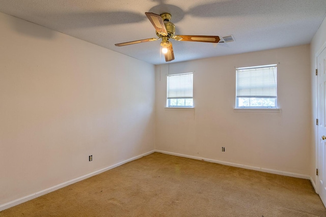 unfurnished room featuring visible vents, baseboards, light carpet, a textured ceiling, and a ceiling fan