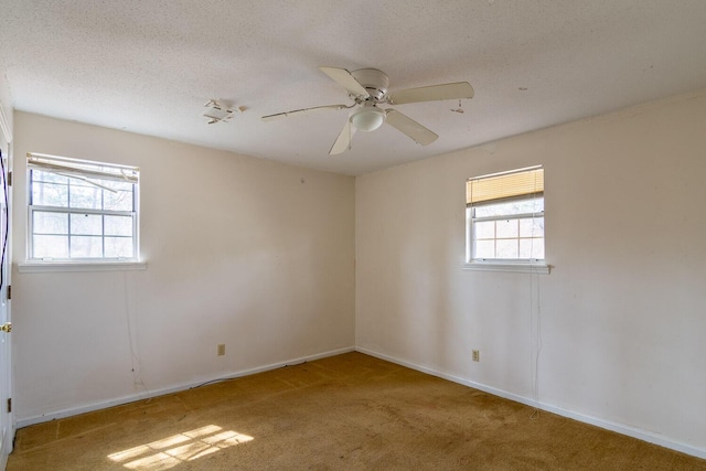 carpeted spare room featuring a ceiling fan, baseboards, and a textured ceiling