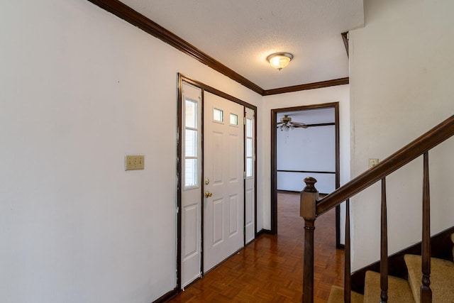 foyer with a textured ceiling, stairs, baseboards, and ornamental molding