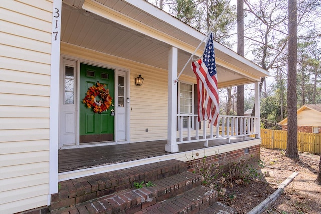 entrance to property with covered porch and fence