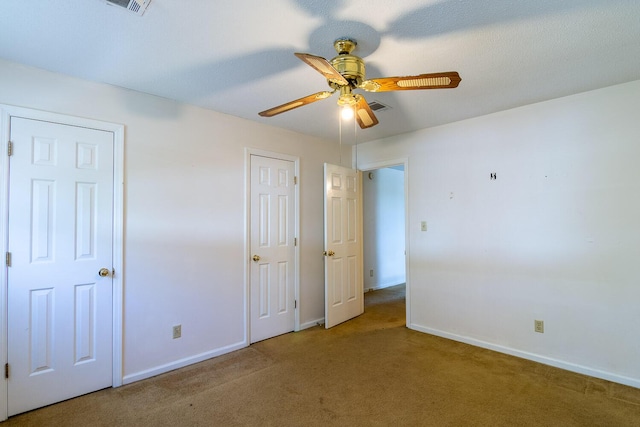 unfurnished bedroom with visible vents, carpet floors, baseboards, and ceiling fan