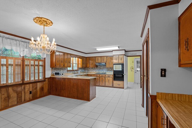 4558 Glenda Ln, Evans, GA 30809 - kitchen with black appliances, brown cabinetry, a peninsula, ornamental molding, and a chandelier
