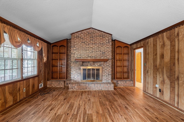4558 Glenda Ln, Evans, GA 30809 - unfurnished living room featuring built in shelves, wooden walls, a textured ceiling, wood finished floors, and lofted ceiling
