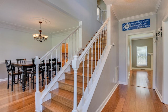 stairs featuring crown molding, hardwood / wood-style floors, and an inviting chandelier