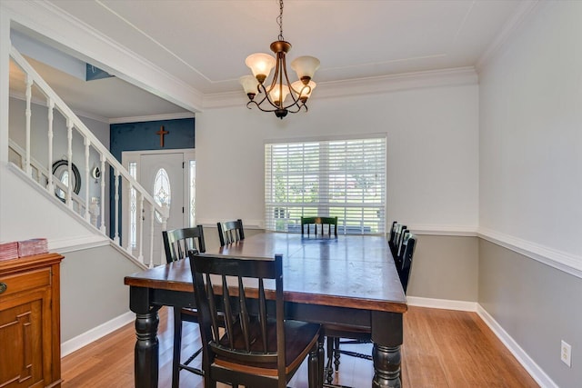 dining area with light hardwood / wood-style floors, ornamental molding, and a chandelier