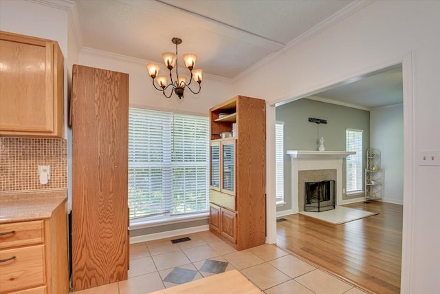 kitchen with crown molding, light tile patterned flooring, pendant lighting, and an inviting chandelier