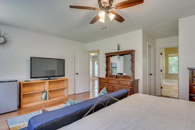 bedroom with ceiling fan, ensuite bathroom, a textured ceiling, fridge, and light wood-type flooring