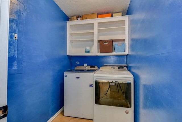 washroom with washing machine and dryer, light tile patterned floors, and a textured ceiling