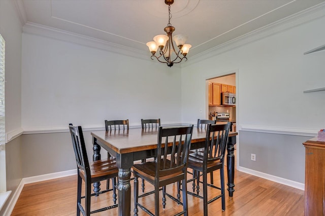 dining area with crown molding, light wood-type flooring, and an inviting chandelier