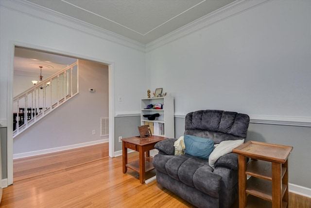 sitting room with a notable chandelier, wood-type flooring, and ornamental molding