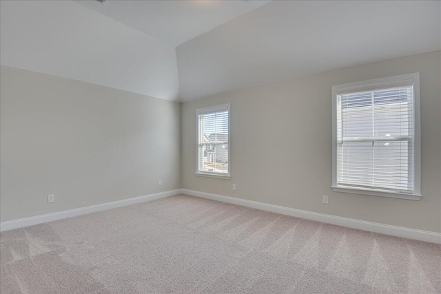 carpeted spare room featuring vaulted ceiling