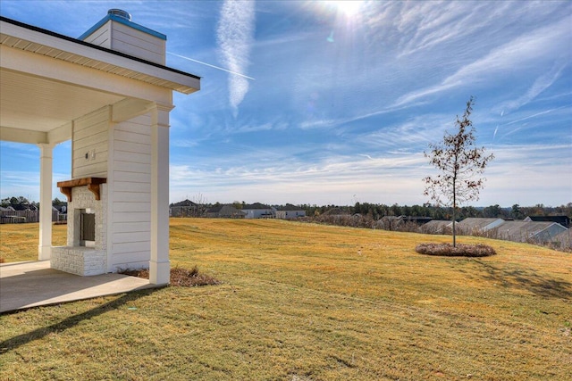 view of yard featuring exterior fireplace and a patio area