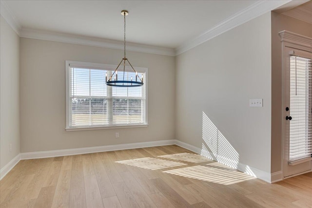 unfurnished dining area featuring crown molding, a chandelier, and light wood-type flooring