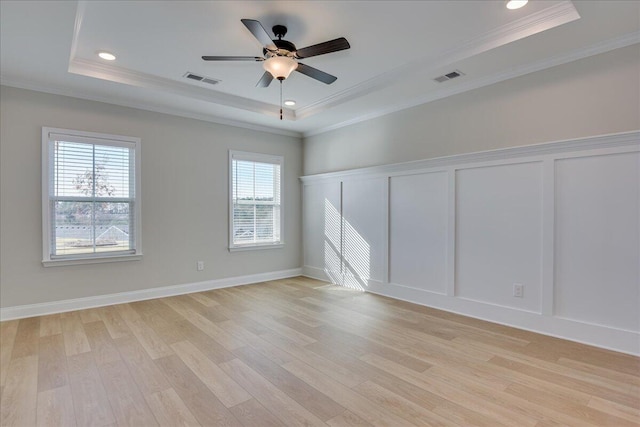 unfurnished room featuring crown molding, a tray ceiling, and a wealth of natural light