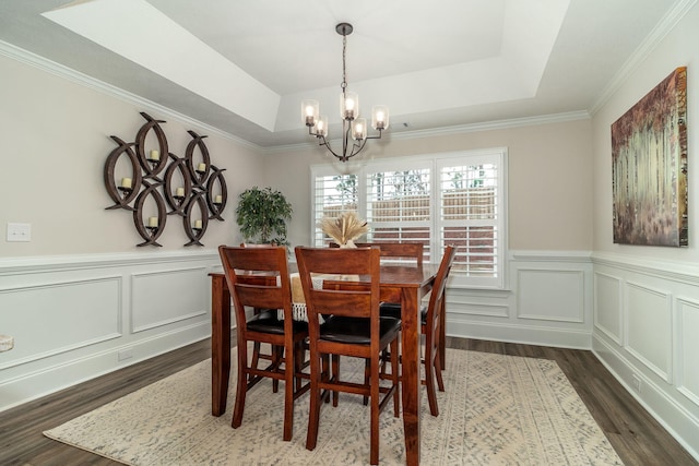 dining room with dark hardwood / wood-style floors, a tray ceiling, crown molding, and a notable chandelier