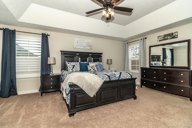 bedroom featuring ceiling fan, light colored carpet, and a raised ceiling