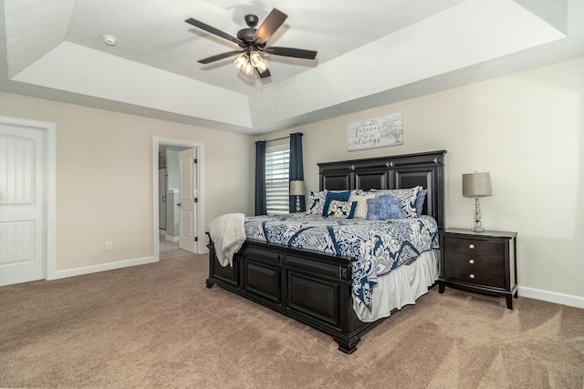 carpeted bedroom featuring ceiling fan and a tray ceiling