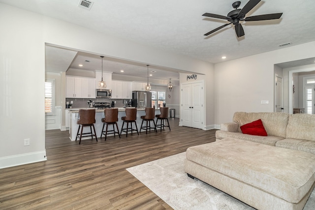 living room with dark wood-type flooring and ceiling fan