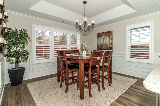 dining room featuring dark wood-type flooring, a raised ceiling, and a wealth of natural light