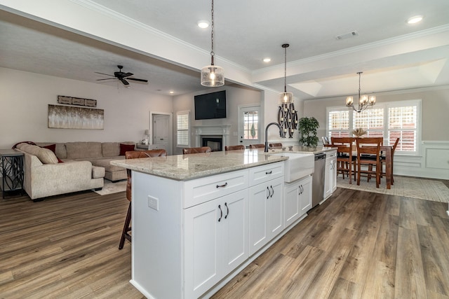 kitchen with sink, white cabinetry, dishwasher, pendant lighting, and a kitchen island with sink