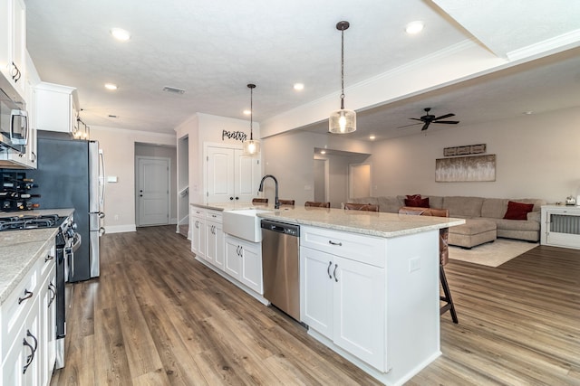 kitchen with appliances with stainless steel finishes, sink, white cabinets, a kitchen bar, and a kitchen island with sink