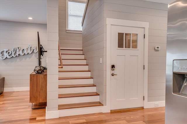 staircase featuring recessed lighting, wood walls, and wood finished floors