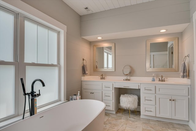 bathroom featuring a sink, a freestanding tub, recessed lighting, and double vanity