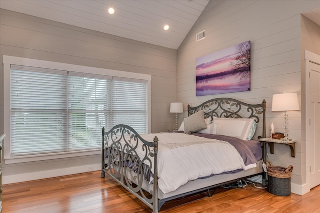 bedroom featuring visible vents, wood walls, lofted ceiling, wood finished floors, and recessed lighting
