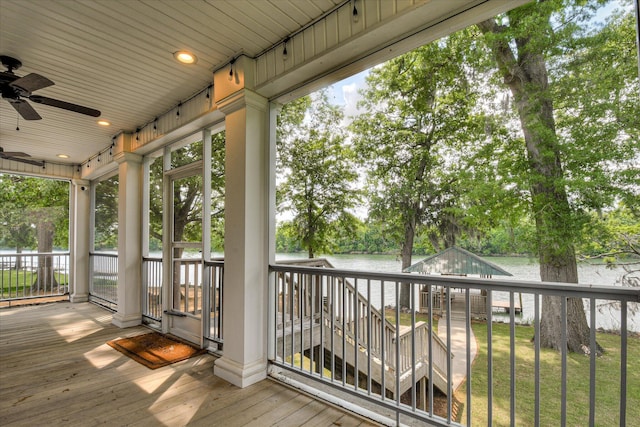 wooden terrace with a water view and ceiling fan